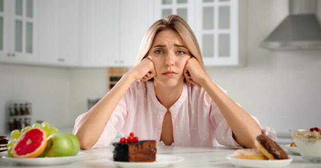 Young woman looking at cake but wanting to avoid sugar