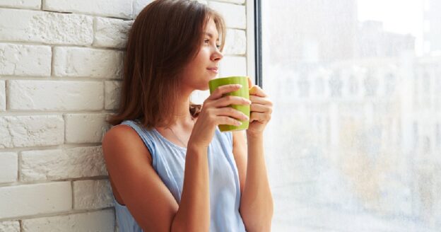 Woman sipping on hot cup of coffee in morning as part of routine